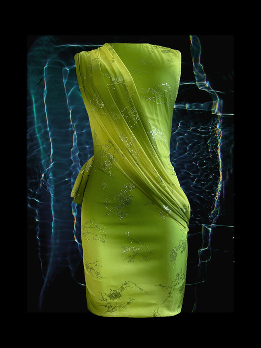 Sleeveless green and yellow ombre short dress. Our mesh floral dress showcase a glitter floral pattern all over. The front of the dress features a sash like wrap across the body and draping around the back.