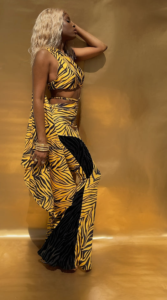 Side view of this yellow and black zebra print flared pants and matching top. This slim flared pants showcase black contrasting panels on one leg. Panels are created out of a black sheer tiger stripe velvet with black glass beads hand sewn in.