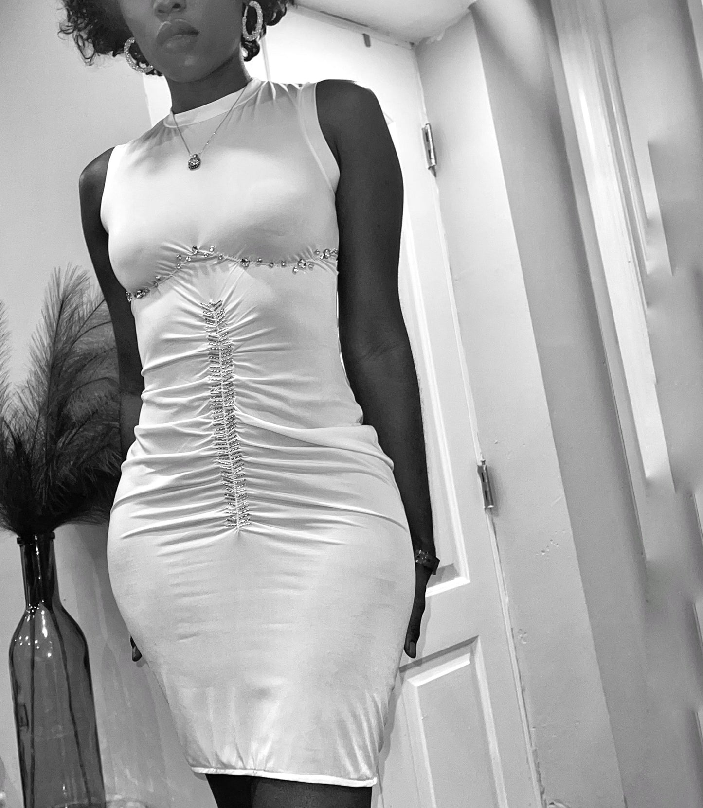 Front view of a semi sheer tank style dress. Dress features rhinestones gathered and hand sewn both under the bust, and center front. The garment features gathers and slight drape. The dress stop short right above the knee.