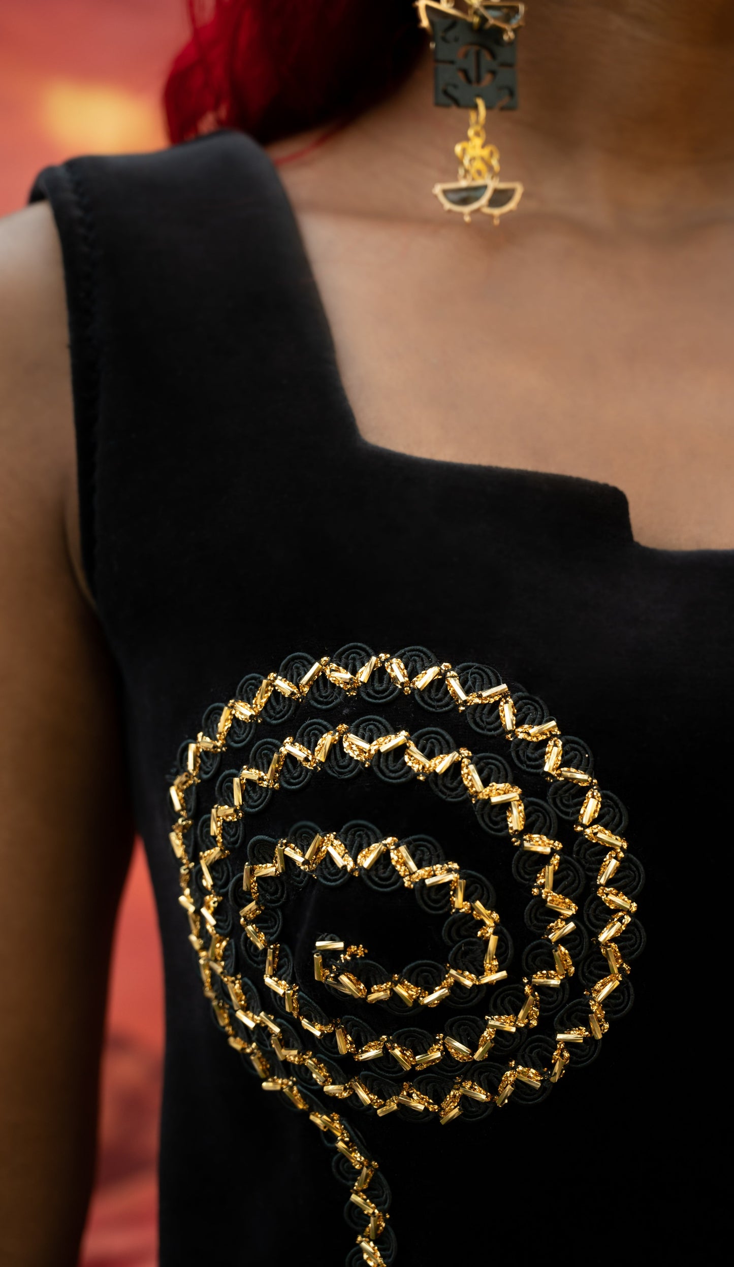 Front view of the dress show case a spiral black and gold design. The spiral circles around the bust before curving straight down to hem line. The spiral is made with a black and gold braided gimp with gold beagle beads.