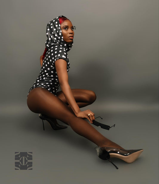 Black and white polka dot bodysuit. This body suit is made out of nylon material. The bodysuit has stretch and has a ruching effect over the tummy and under bust. There are also slight gathering on the shoulders. This bodysuit is a short sleeve, with a hood that you can pull your ponytail out of.