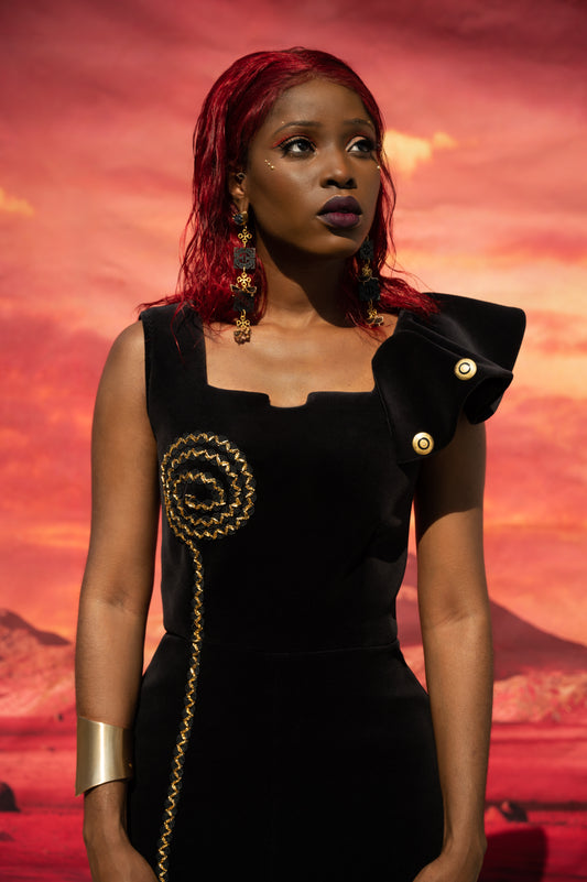 This velveteen garment showcase a regal square neckline, and flounce on one side of the shoulder. The flounce details art deco black and gold circle disc, and compliments the gold glass beaded trim that follows on the corresponding side.